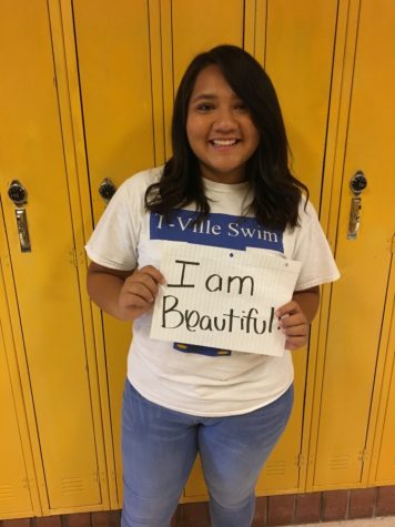 Student holds up sign saying she's beautiful in the way she is.