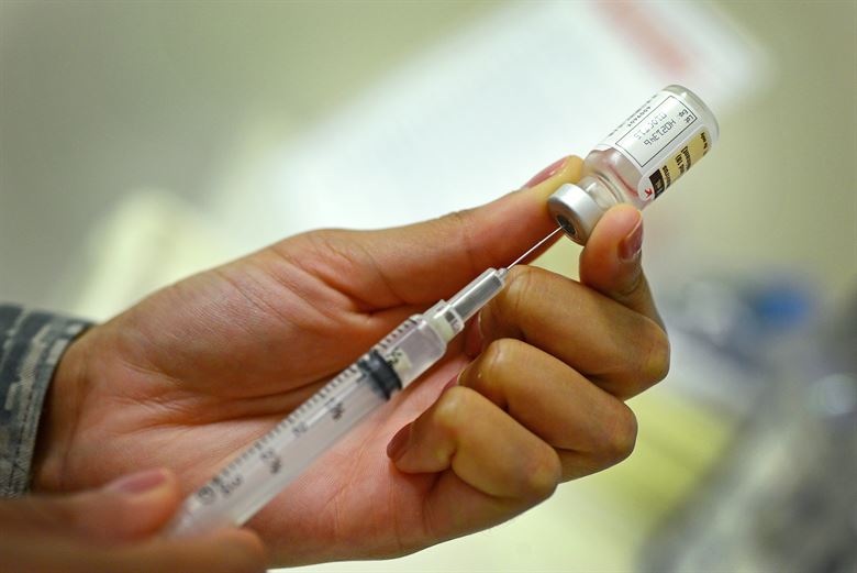 A hand holding a syringe for vaccines