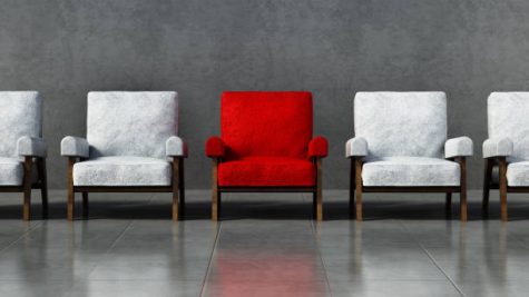 A red chair stands out among a line of white chairs.
