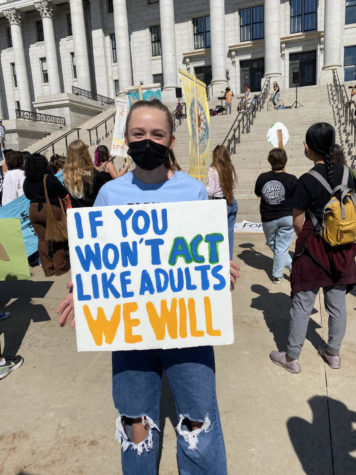 Student holding sign stating, If you dont act like adults we will.